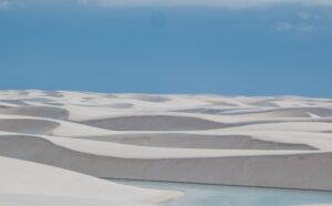 a large expanse of sand dunes with a body of water in the distance