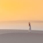 a woman standing on top of a sandy beach