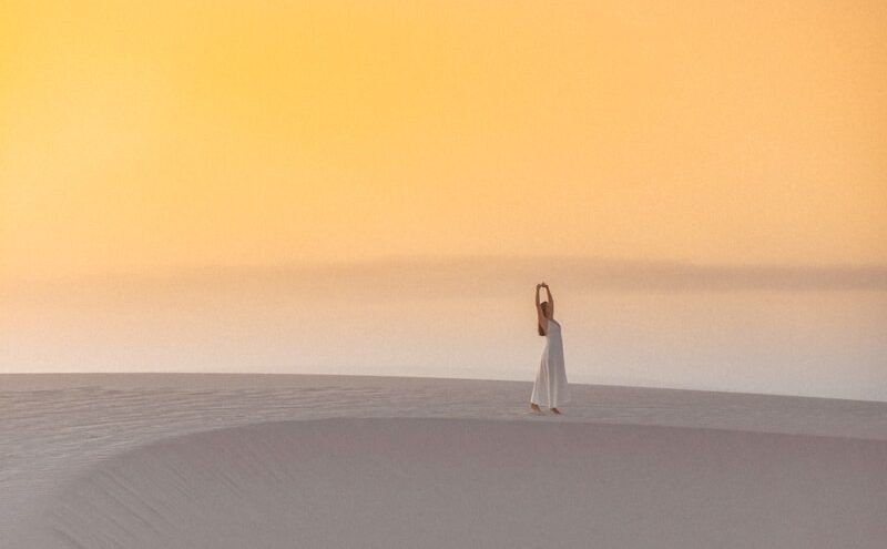 a woman standing on top of a sandy beach