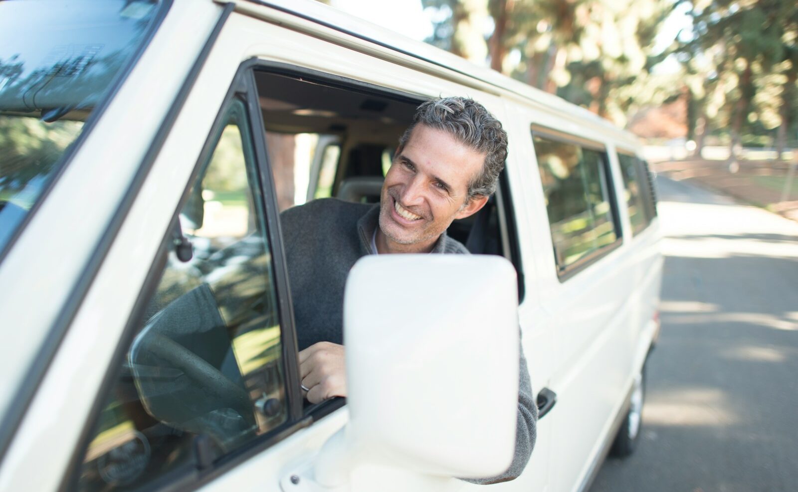 man in gray sweater leaning on van window
