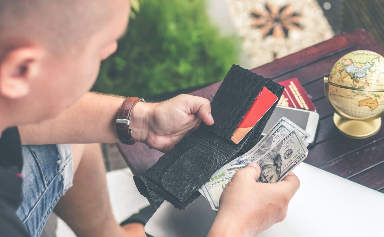 person holding wallet and US dollar bills