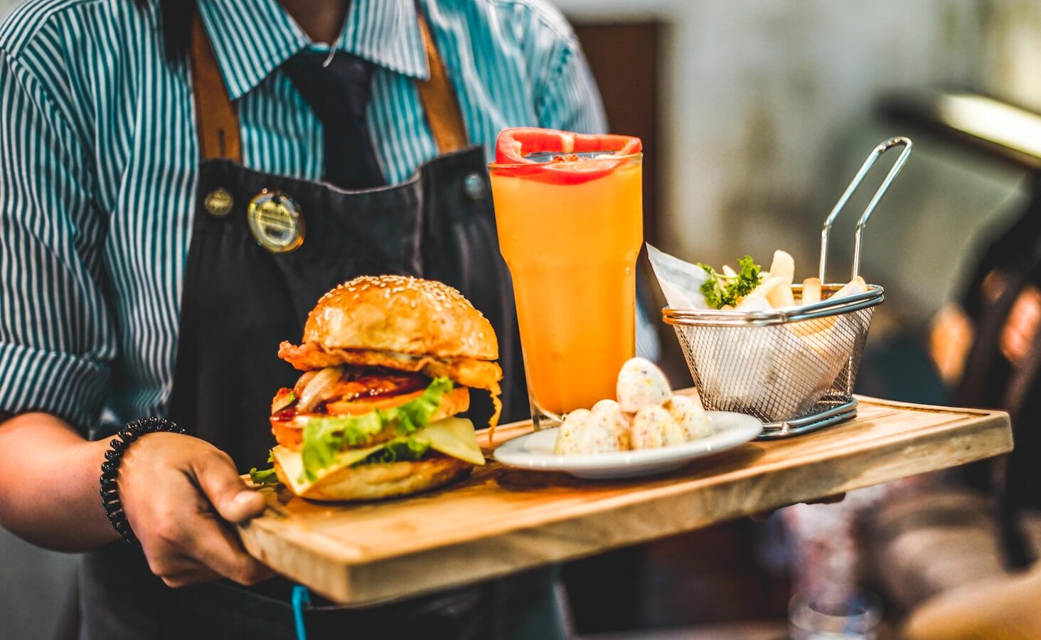 person serving burger with pitcher of juice