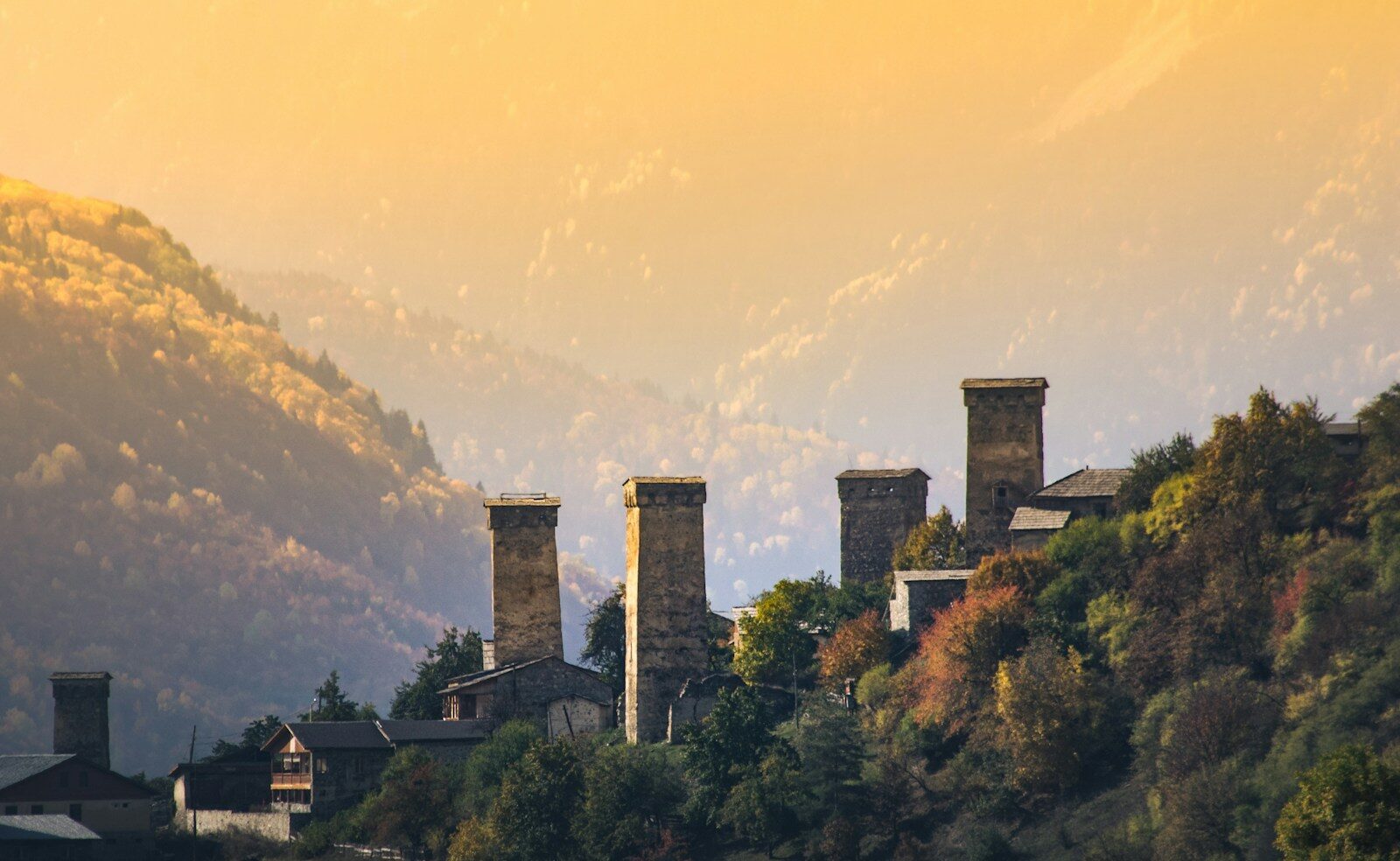 a row of towers on a hillside with a mountain in the background