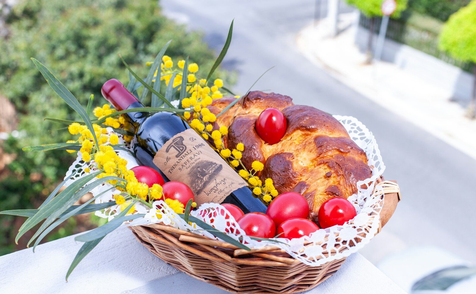 a basket filled with bread, tomatoes and a bottle of wine