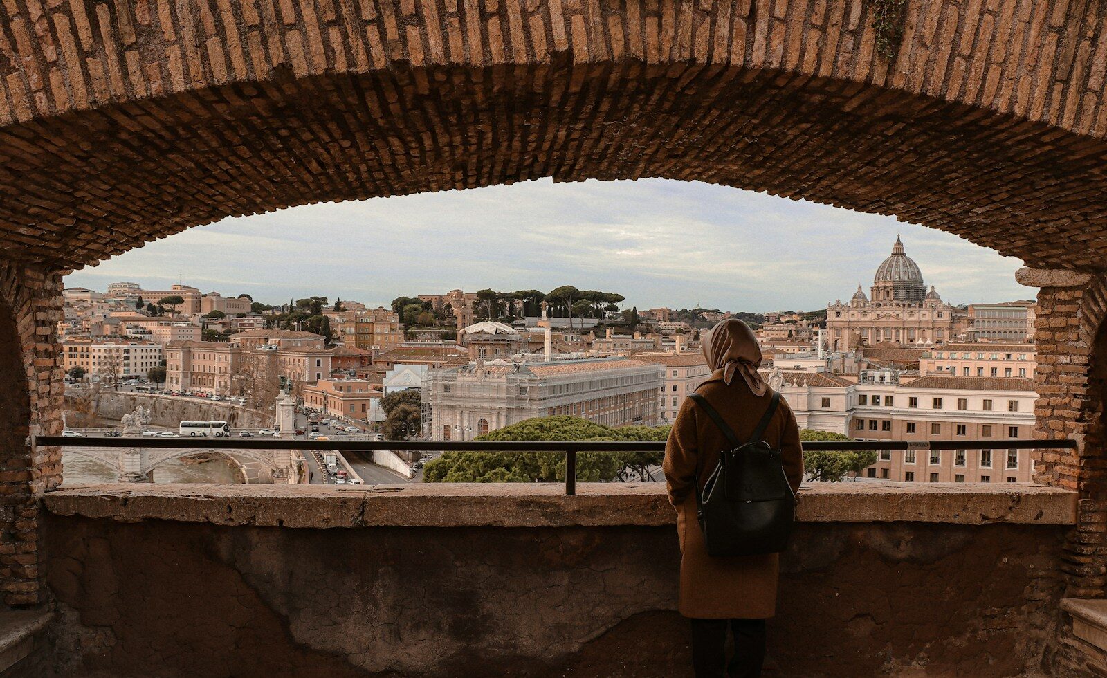 woman in black jacket standing on brown concrete bridge during daytime